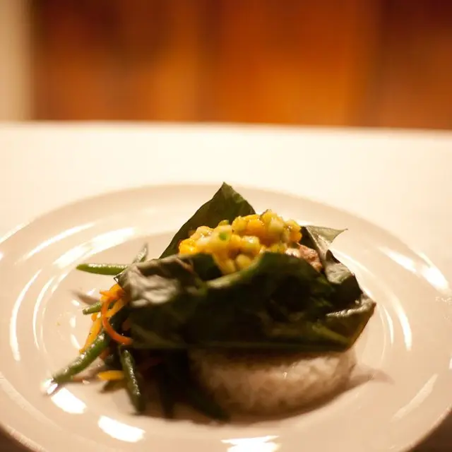 Fish steamed in a banana leaf over coconut rice, with green beans and mango salsa